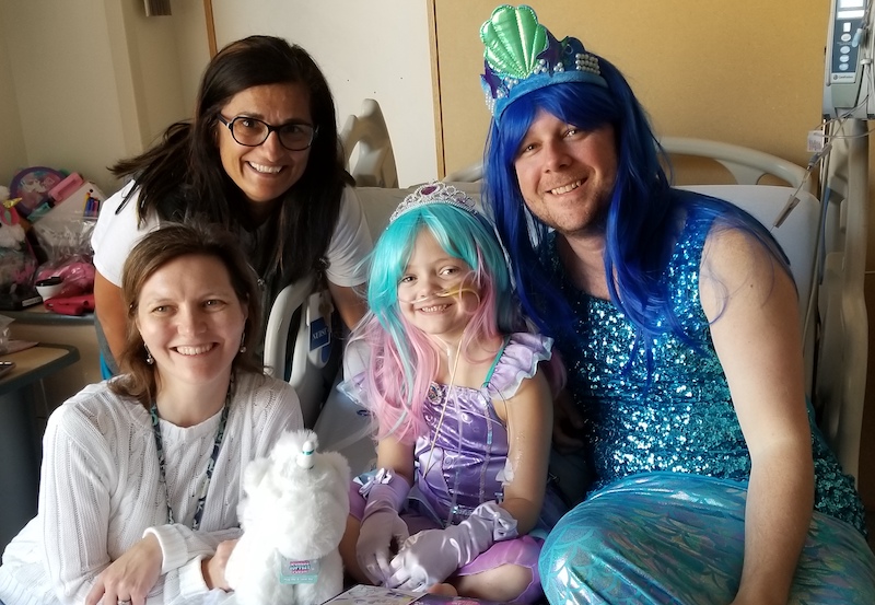 Caitlyn, dressed as a mermaid, with her care team