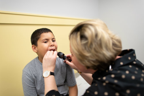 a boy getting his throat examined by a doctor