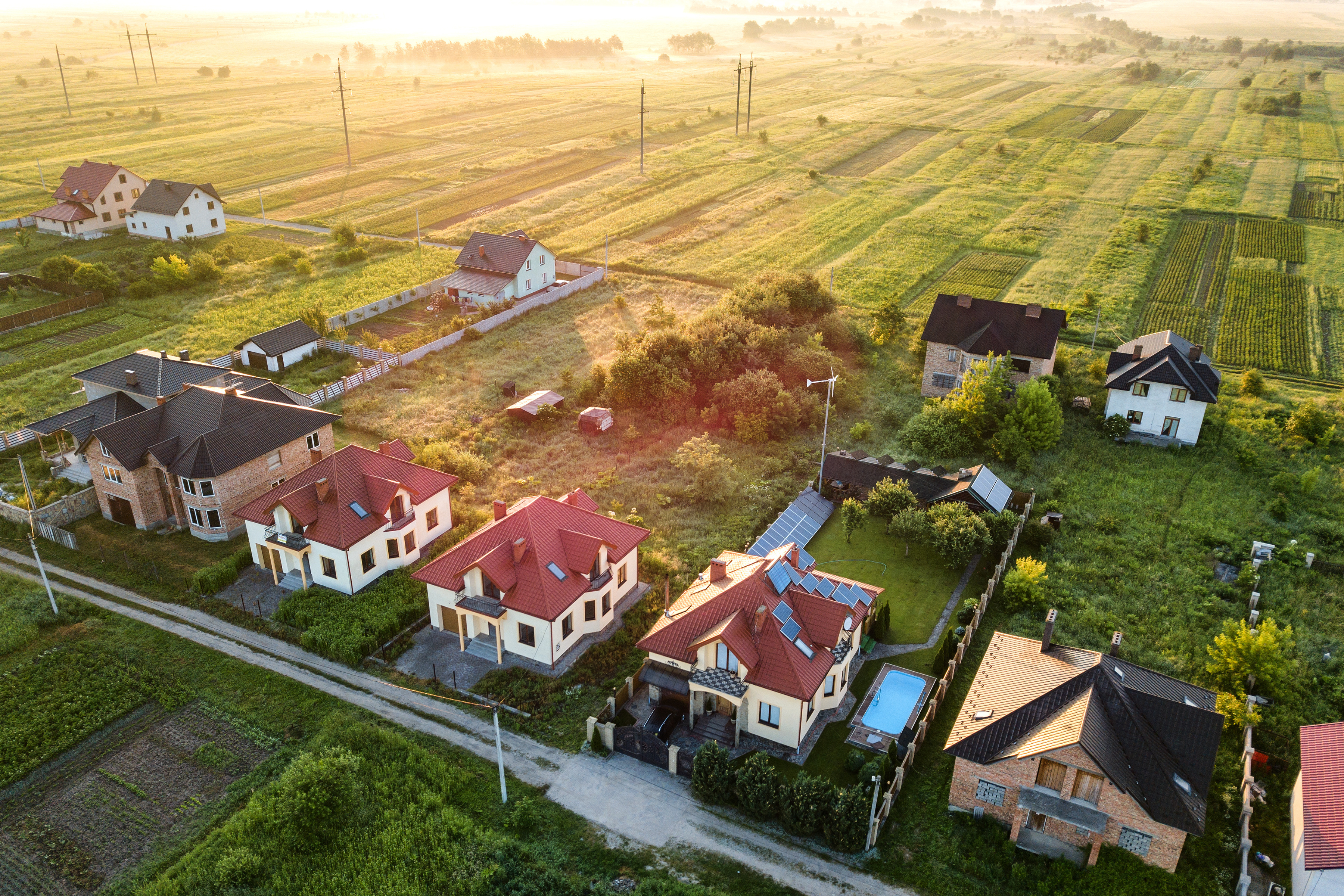 An image of houses in a row with a lot of green farmland behind them. 