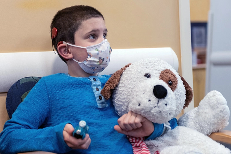 a boy with a cochlear implant holding a stuffed dog
