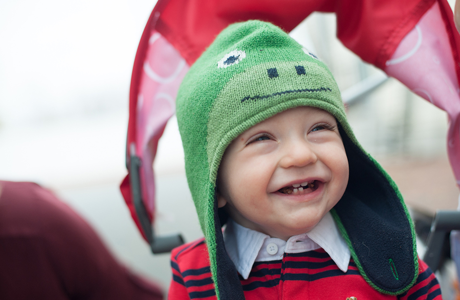 Smiling young boy wears frog hat