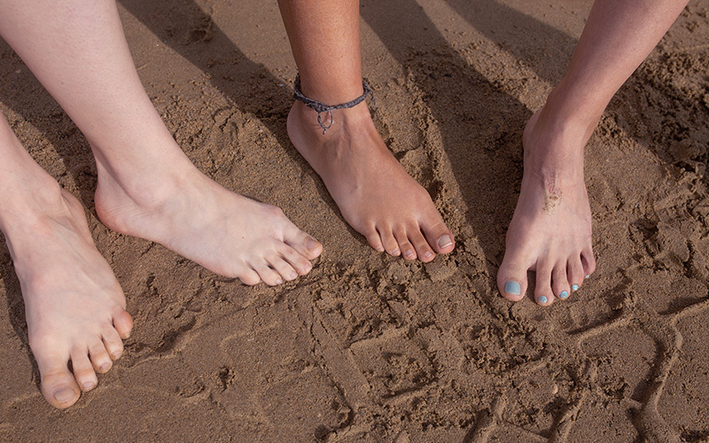 Feet of teenagers in sand