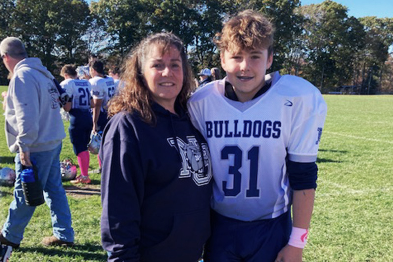 Player in football jersey stands with his mom after a game