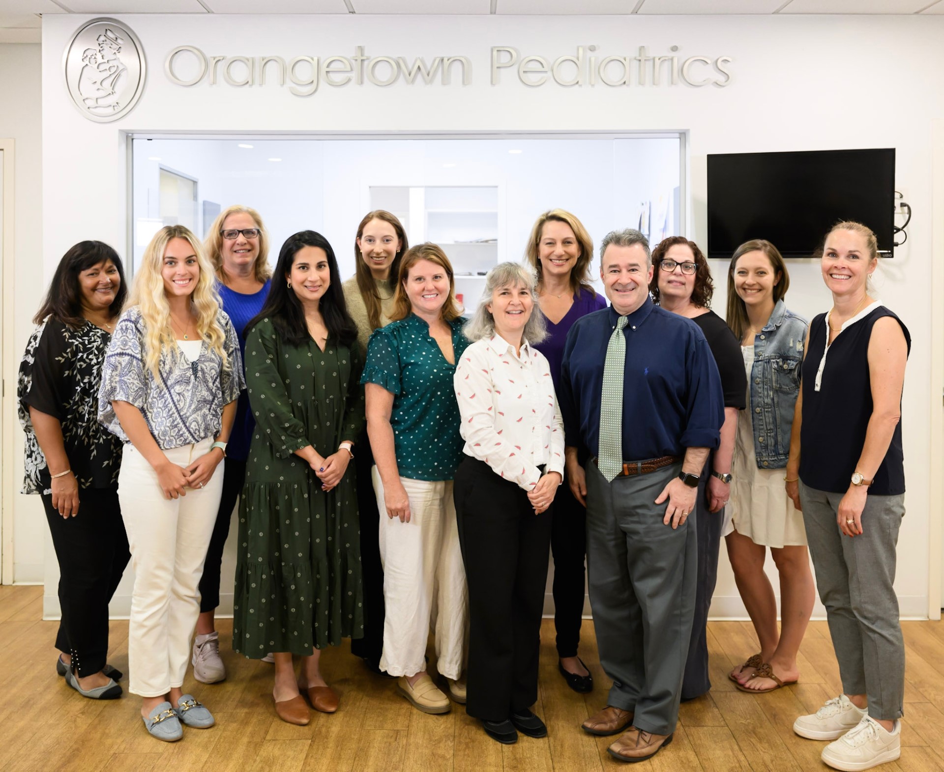 a group of medical professionals smiling at the camera in front of a sign that says 'orangetown pediatrics'