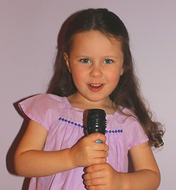 Young girl in pink dress holds microphone