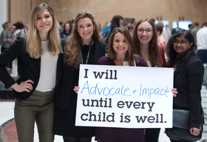 Women hold sign reading: "I will advocate and impact until every child is well."