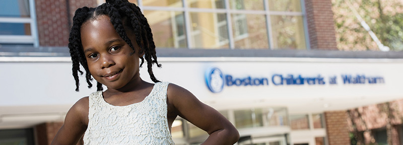 Young girl stands in front of Boston Children's Waltham
