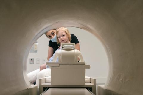 Child and clinician look at inside of MRI machine